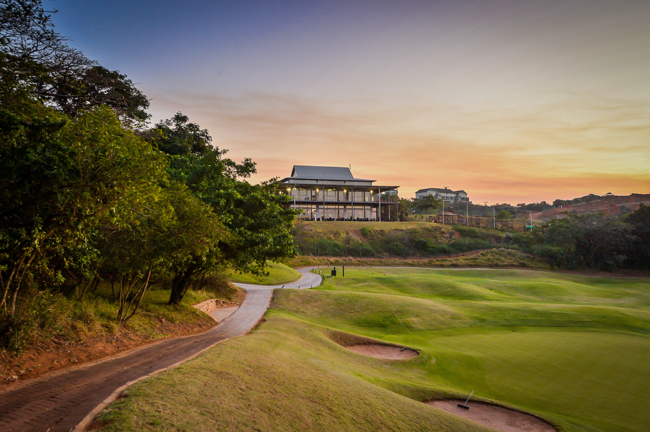 A golf course with a building and treesDescription automatically generated