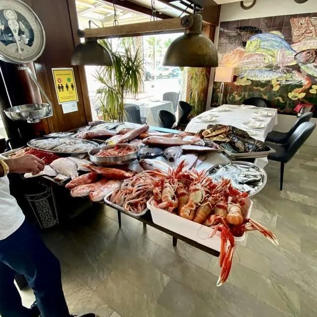 A person standing next to a table full of seafoodDescription automatically generated